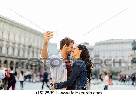 Stock Image - Couple taking selfie, Piazza del Duomo, Milan, Italy. Fotosearch