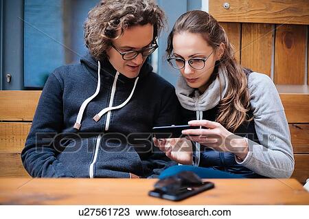 Couple using smartphone in cafe View Large Photo Image Stock Image - Couple using smartphone in cafe. Fotosearch