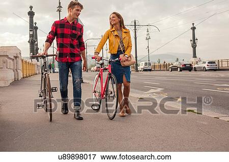Couple walking bicycles across bridge, Budapest, Hungary View Large Photo Image Stock Photo - Couple walking bicycles across bridge, Budapest, Hungary. Fotosearch