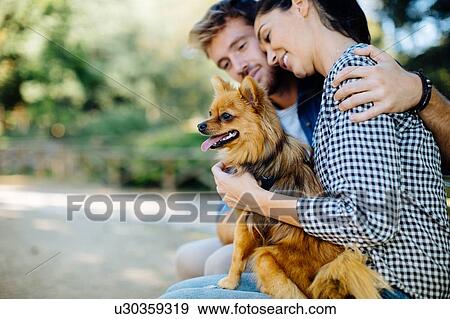 Stock Photo - Couple with pet dog in park. Fotosearch