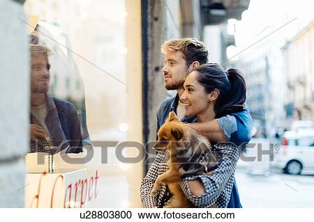 Stock Image - Couple with pet dog window-shopping, Milan, Italy. Fotosearch