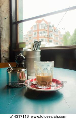 Stock Photograph - Cutlery and unfinished glass of latte by cafe window, London, UK. Fotosearch