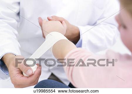 Picture - Doctor bandaging girl's wrist.. Fotosearch