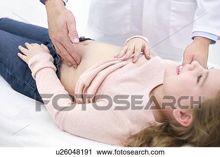 Stock Image - Doctor examining girl's abdomen. Fotosearch