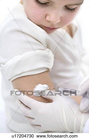 Stock Image - Doctor holding cotton wool on young girl's arm after injection.. Fotosearch