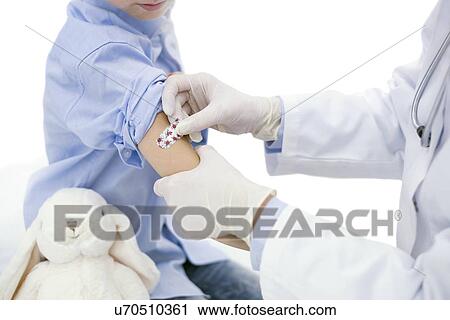 Doctor putting plaster on boy's arm after injection. View Large Photo Image Stock Image - Doctor putting plaster on boy's arm after injection.. Fotosearch
