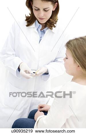 Stock Photo - Doctor testing young girl using finger prick test.. Fotosearch