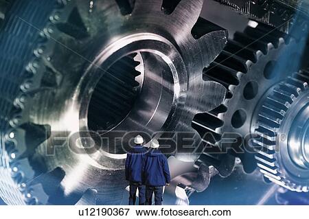 Stock Photo - Engineering, conceptual image. Two industry workers with large gears and cog machinery powered by chains.. Fotosearch