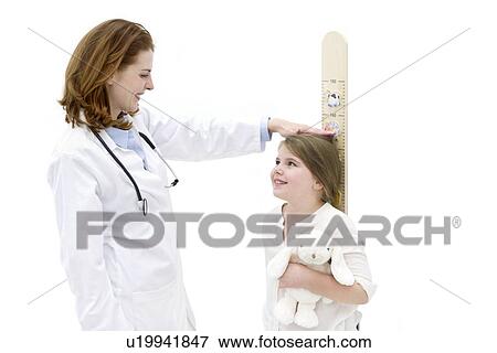 Stock Photo - Female doctor measuring young girl on height chart.. Fotosearch