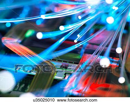 Stock Image - Fibre optic strands carrying data over electronic circuit board of laptop computer. Fotosearch
