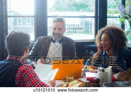 Stock Photography - Friends at breakfast meeting in cafe, London, UK. Fotosearch