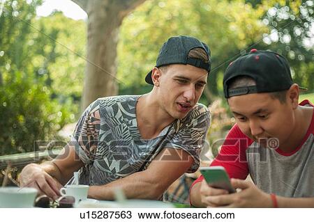 Friends reading text message in park View Large Photo Image Stock Image - Friends reading text message in park. Fotosearch