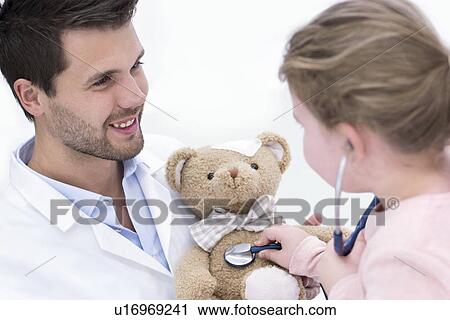 Stock Image - Girl playing with teddy bear and stethoscope.. Fotosearch