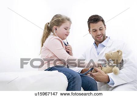 Stock Photo - Girl playing with teddy bear and stethoscope.. Fotosearch