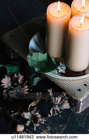 Stock Image - Lit candles on rustic cutting board. Fotosearch