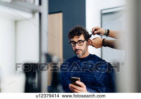 Male hairstylist cutting male customer's hair in hair salon View Large Photo Image Picture - Male hairstylist cutting male customer's hair in hair salon. Fotosearch
