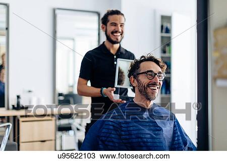 Male hairstylist showing male customer's hair in in hand mirror at hair salon View Large Photo Image Stock Image - Male hairstylist showing male customer's hair in in hand mirror at hair salon. Fotosearch