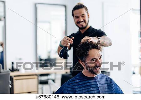 Male hairstylist spraying male customer's hair in hair salon View Large Photo Image Stock Photograph - Male hairstylist spraying male customer's hair in hair salon. Fotosearch