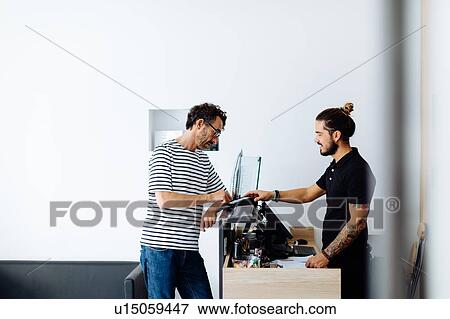 Male hairstylist taking male customer's credit card payment at hair salon View Large Photo Image Stock Photo - Male hairstylist taking male customer's credit card payment at hair salon. Fotosearch