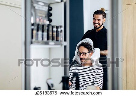 Stock Photography - Male hairstylist towel drying male customer's hair in hair salon. Fotosearch