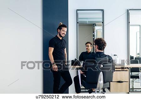 Stock Image - Male hairstylists chatting in hair salon. Fotosearch