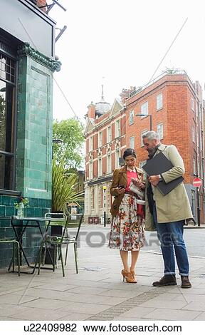 Stock Image - Man and woman checking cellphones, London, UK. Fotosearch