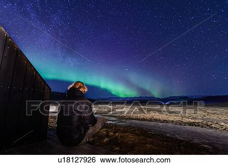 Man sitting in front of northern lights, Skogar, Iceland View Large Photo Image Stock Photograph - Man sitting in front of northern lights, Skogar, Iceland. Fotosearch