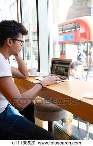 Stock Image - Man using laptop in cafe. Fotosearch