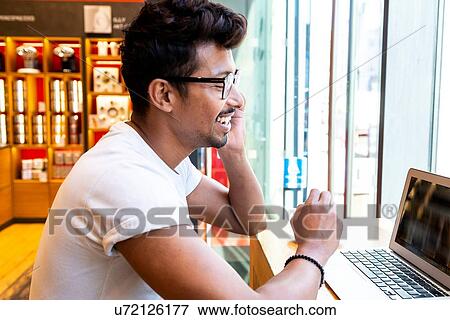 Stock Photo - Man using laptop in cafe. Fotosearch