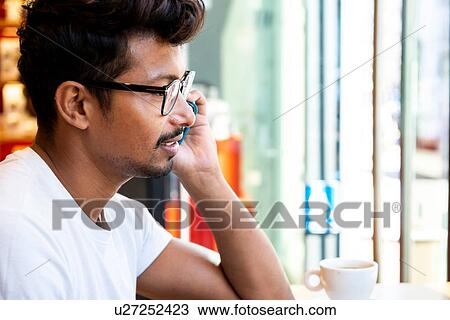 Stock Image - Man using smartphone in cafe. Fotosearch