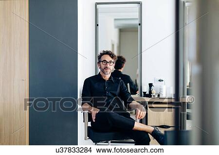 Mature male hairstylist sitting in chair in hair salon, portrait View Large Photo Image Picture - Mature male hairstylist sitting in chair in hair salon, portrait. Fotosearch