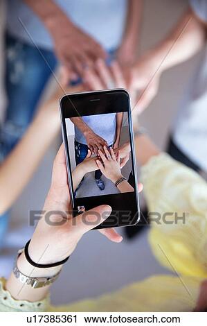 Stock Image - Photographing with smartphone of overlapping hands. Fotosearch