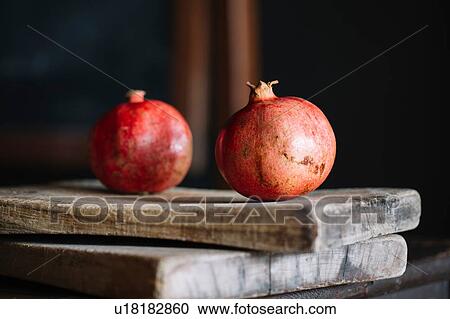 Stock Image - Pomegranates on rustic chopping boards, still life. Fotosearch