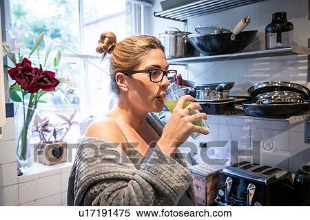 Stock Photography - Pregnant mid adult woman drinking fresh juice in kitchen. Fotosearch