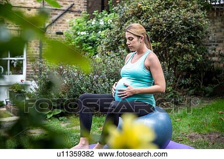 Pregnant mid adult woman sitting on exercise ball in garden View Large Photo Image Stock Image - Pregnant mid adult woman sitting on exercise ball in garden. Fotosearch