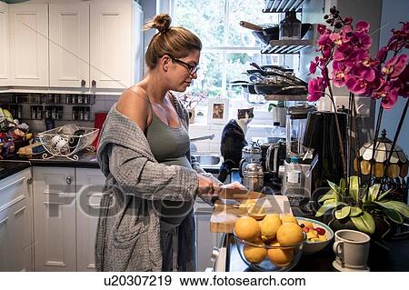 Pregnant mid adult woman slicing an orange in kitchen View Large Photo Image Stock Photo - Pregnant mid adult woman slicing an orange in kitchen. Fotosearch