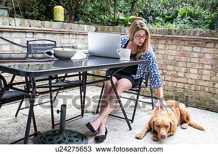 Pregnant mid adult woman using at laptop on patio table while petting dog View Large Photo Image Stock Image - Pregnant mid adult woman using at laptop on patio table while petting dog. Fotosearch
