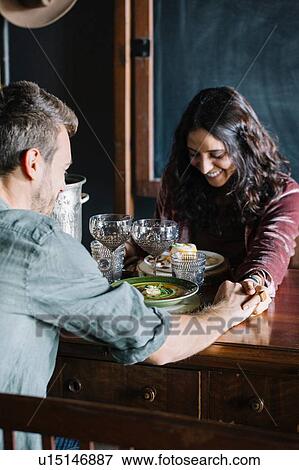 Romantic young couple having a meal, holding hands across table View Large Photo Image Stock Photo - Romantic young couple having a meal, holding hands across table. Fotosearch
