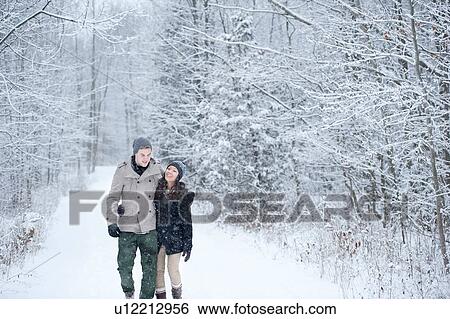 Stock Photograph - Romantic young couple strolling in snowy forest, Ontario, Canada. Fotosearch