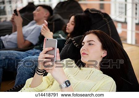 School friends lying on beanbags and texting at school View Large Photo Image Stock Image - School friends lying on beanbags and texting at school. Fotosearch
