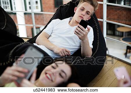 School friends lying on beanbags and texting at school View Large Photo Image Stock Image - School friends lying on beanbags and texting at school. Fotosearch