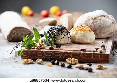 Seeded bread rolls and rustic loaves on chopping board, still life View Large Photo Image Picture - Seeded bread rolls and rustic loaves on chopping board, still life. Fotosearch
