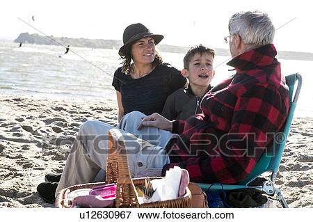 Stock Photo - Senior adult man with daughter and grandson enjoying beach. Fotosearch