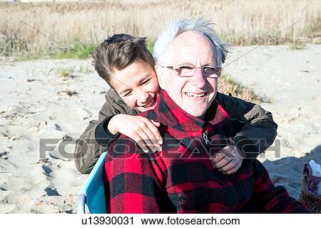 Stock Image - Senior adult man with grandson enjoying beach. Fotosearch