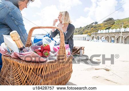 Stock Photo - Sisters enjoying picnic on beach. Fotosearch