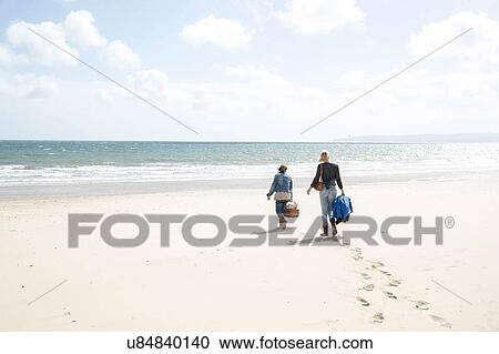 Stock Image - Sisters leaving after picnic on beach. Fotosearch