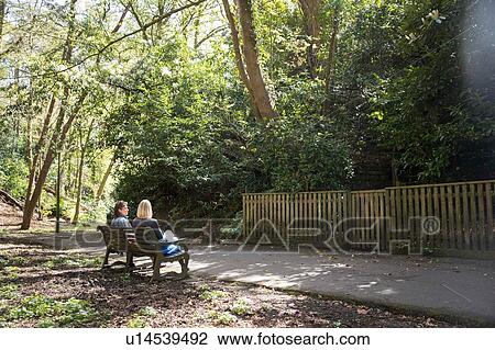Stock Image - Sisters sitting on park bench. Fotosearch