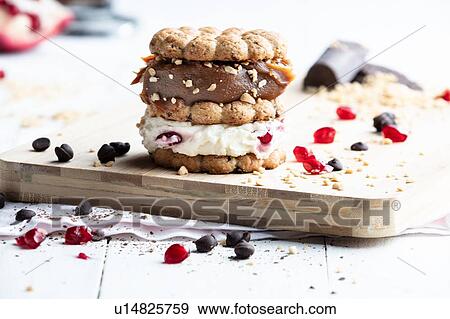 Stock Photo - Stacked cookie with cream and caramel on chopping board, still life. Fotosearch