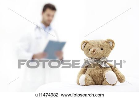 Teddy bear with male doctor in background holding clipboard. View Large Photo Image Stock Image - Teddy bear with male doctor in background holding clipboard.. Fotosearch