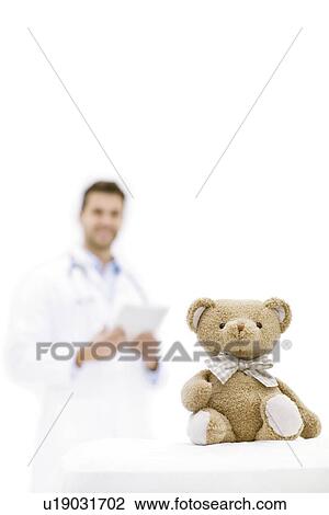Stock Image - Teddy bear with male doctor in background.. Fotosearch